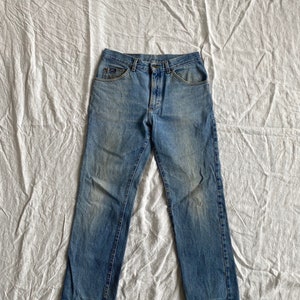 May include: A pair of light blue denim jeans with a faded look. The jeans have a classic five-pocket style and a straight leg.