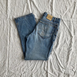 May include: A pair of blue denim jeans with a brown leather Lee label on the back pocket.