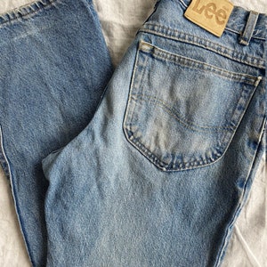 May include: A pair of light blue denim jeans with a brown leather patch that says "Lee" on the back pocket.