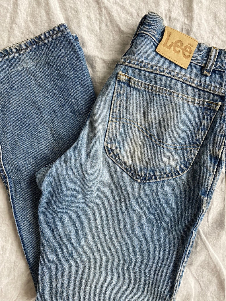 May include: A pair of light blue denim jeans with a brown leather patch that says "Lee" on the back pocket.