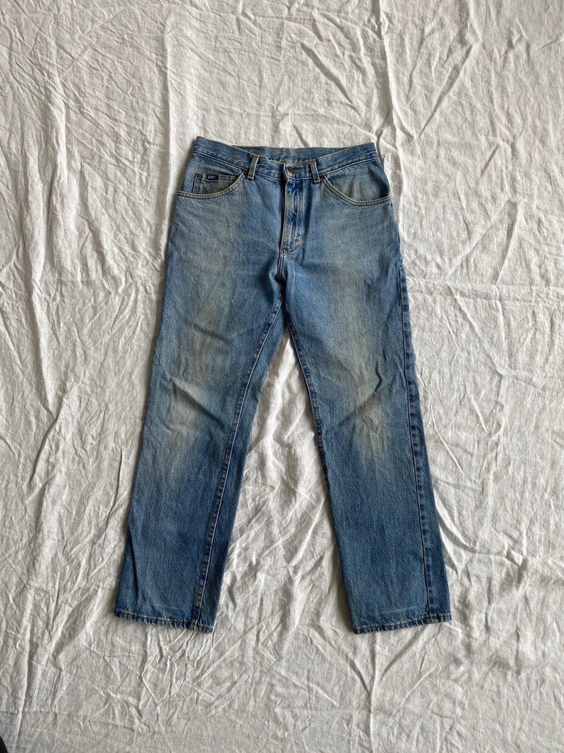 May include: A pair of light blue denim jeans with a faded look. The jeans have a classic five-pocket style and a straight leg.