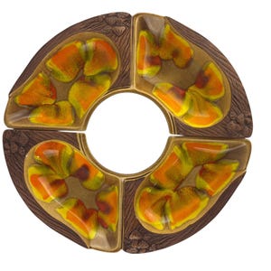 May include: A circular, segmented serving dish with a central opening. The dish is composed of four curved sections. Each section has a brown, textured exterior with floral carvings and a glazed interior featuring orange, yellow, and green abstract designs.