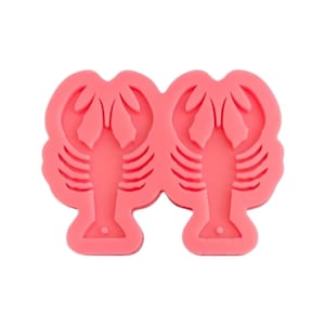 May include: Pink silicone mold for making two lobster-shaped treats. The mold has a detailed design of the lobster's body and claws.