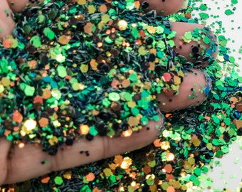 May include: Green, gold, and iridescent glitter in various sizes and shapes. The glitter is scattered on a white surface.