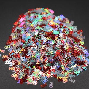 May include: A pile of iridescent red, silver, and green glitter shaped like the letters "HO".