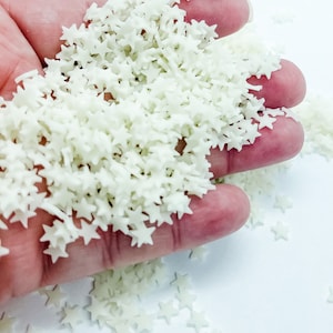 May include: A handful of white star-shaped sprinkles. The sprinkles are small and have a slightly iridescent sheen.