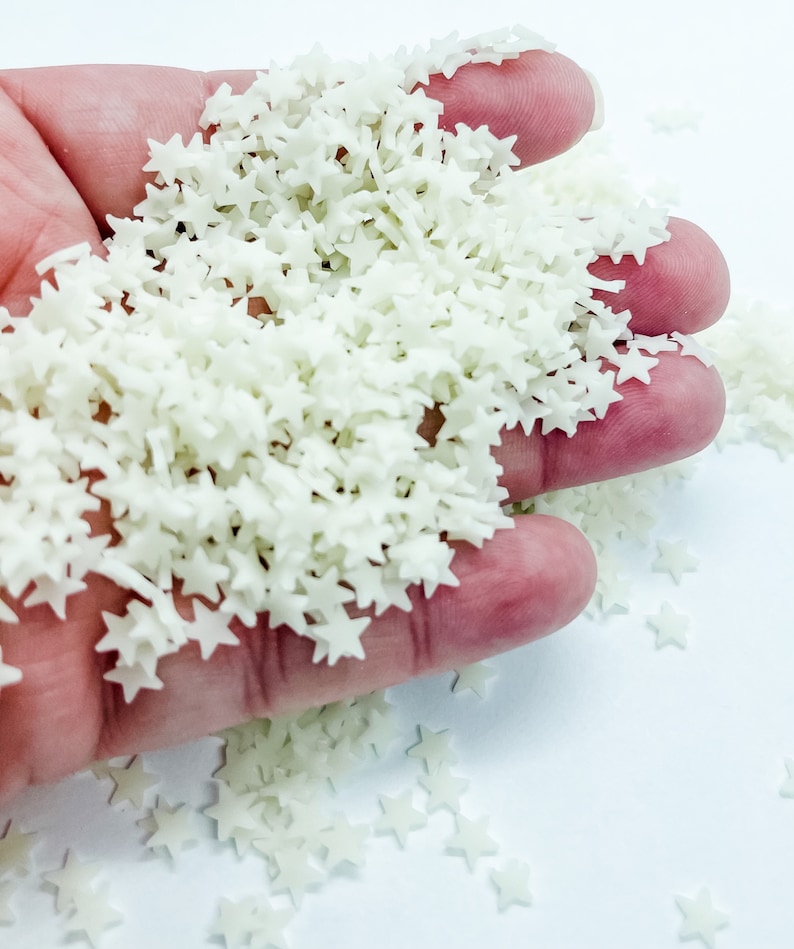 May include: A handful of white star-shaped sprinkles. The sprinkles are small and have a slightly iridescent sheen.