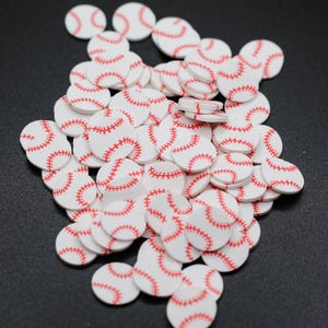 May include: A pile of white and red baseball-themed embellishments. The embellishments are round and have a red stitching design.