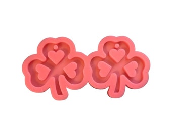 Puede incluir: Molde de silicona rosa de dos tréboles de cuatro hojas con corazones en el centro de cada hoja.