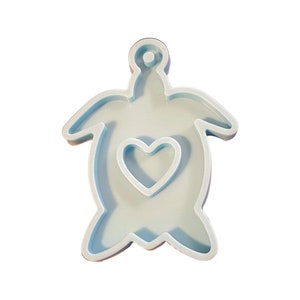 May include: A light blue silicone mold shaped like a turtle with a heart cutout in the center. The mold is designed for making resin crafts.