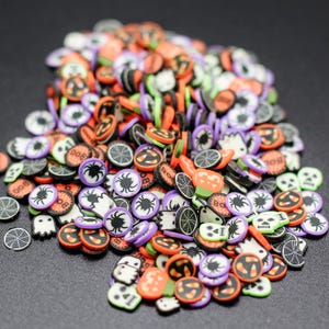 May include: A large assortment of Halloween themed sprinkles in various colors, including black, orange, green, purple, and white. The sprinkles feature various Halloween designs, including ghosts, pumpkins, spiders, and candy corn.