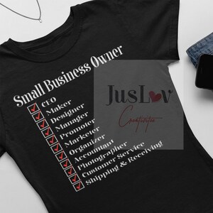 May include: Black t-shirt with the text "Small Business Owner" and a checklist of tasks including CEO, Maker, Designer, Manager, Promoter, Marketer, Organiser, Accountant, Photographer, Customer Service, and Shipping & Receiving. The text "JusLov Creativities" is also on the shirt.