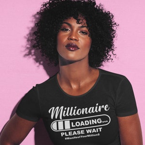 Puede incluir: Camiseta negra con un gráfico blanco que dice "Millionaire Loading... Please Wait #ManifestYourMillions"