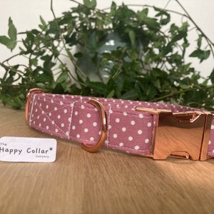 May include: A pink and white polka dot dog collar with a rose gold buckle. The collar is labeled "The Happy Collar Company".