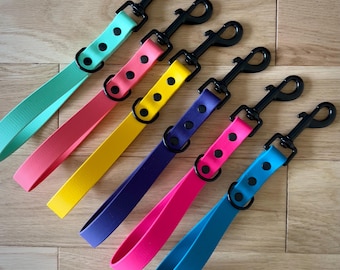 Op de afbeelding: Zes kleurrijke hondenriemen met zwarte metalen clips en zwarte stippen. De riemen zijn turquoise, roze, geel, paars, teal en koraal.