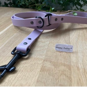 May include: A lavender leather dog leash with black hardware and a black metal clip. The leash has a tag that says "The Happy Collar Company".