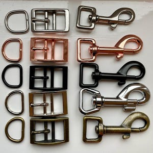 May include: Assortment of silver, gold, and black metal dog leash hardware, including D-rings, buckles, and clasps.