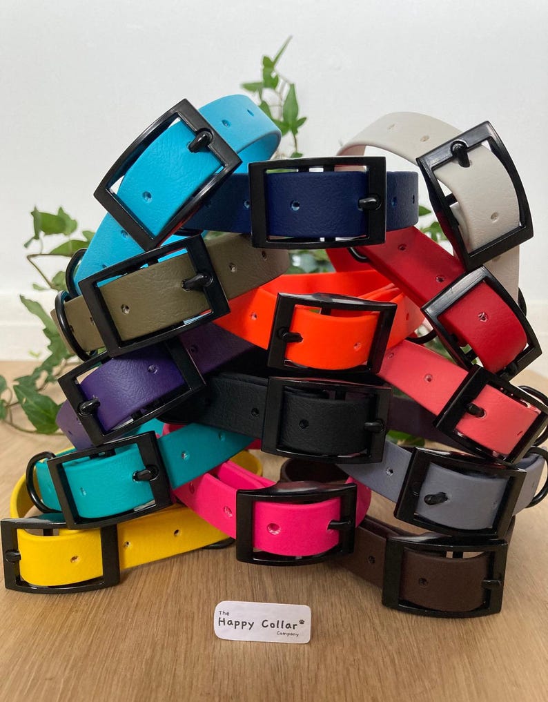 May include: A stack of colorful rubber dog collars with black buckles. The collars are in various colors, including blue, green, orange, red, purple, pink, yellow, and gray. The collars are arranged in a pile, with the buckles facing up. The text "The Happy Collar Company" is visible at the bottom of the image.