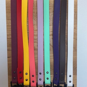 May include: Ten colorful dog leashes with black metal clips. The leashes are made of a rubber-like material and come in a variety of colors, including purple, red, yellow, pink, light purple, green, blue, brown, white, and black.