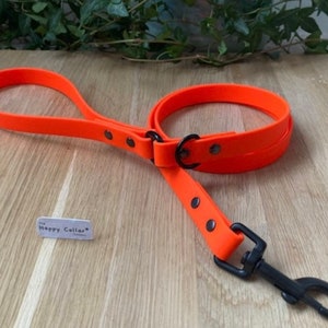 May include: Orange rubber dog leash with a black metal clip and a black metal ring. The leash has a black label with the text "The Happy Collar" on it.