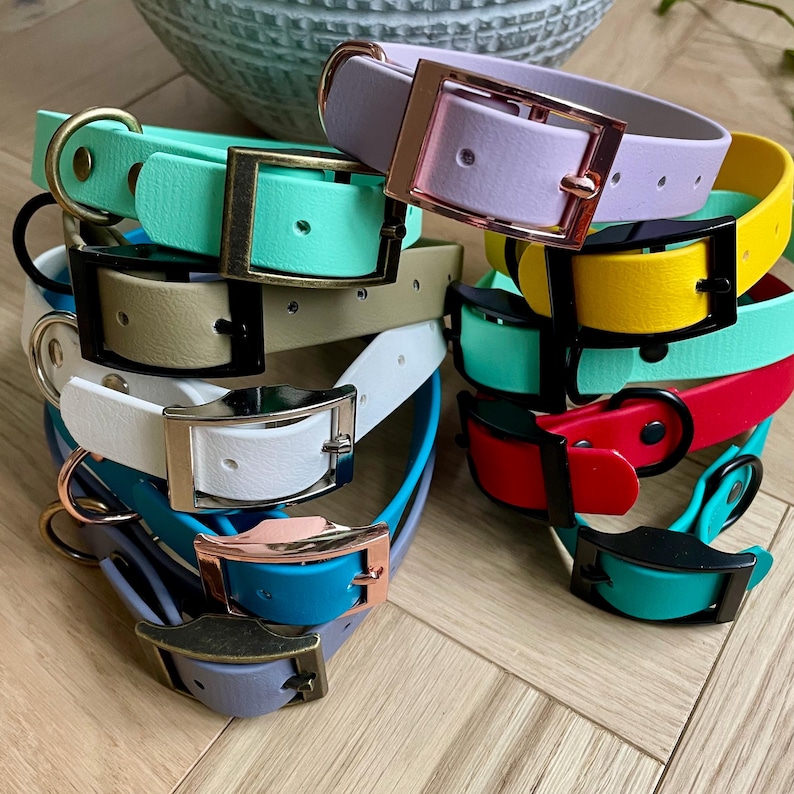 May include: A stack of colorful dog collars with different buckle styles. The collars are made of a rubber-like material and come in a variety of colors, including teal, white, yellow, red, and lavender.
