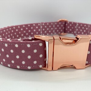 May include: A pink and white polka dot dog collar with a rose gold buckle.