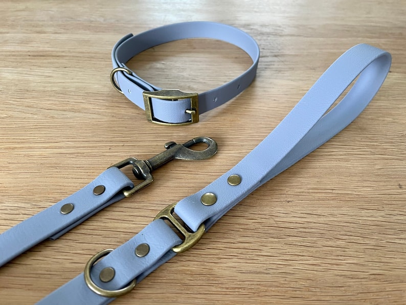 May include: A light purple leather dog collar and leash set with brass hardware. The collar has a buckle closure and the leash has a clip.