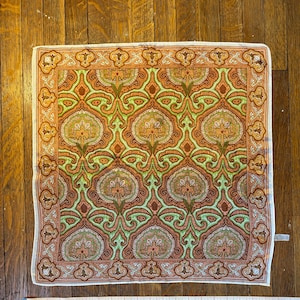 Peut inclure: Un foulard carré en soie blanche avec un motif paisley dans des tons de brun, vert et crème. Le motif présente des motifs floraux et géométriques complexes.