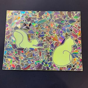 May include: A mosaic artwork made from iridescent pieces of broken CDs, with two light green cat silhouettes on a light green background.