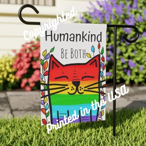 Könnte beinhalten: Eine farbenfrohe Gartenflagge mit einem Regenbogen-Katzen-Design und dem Text "HumanKind Be Both", gedruckt in den USA.
