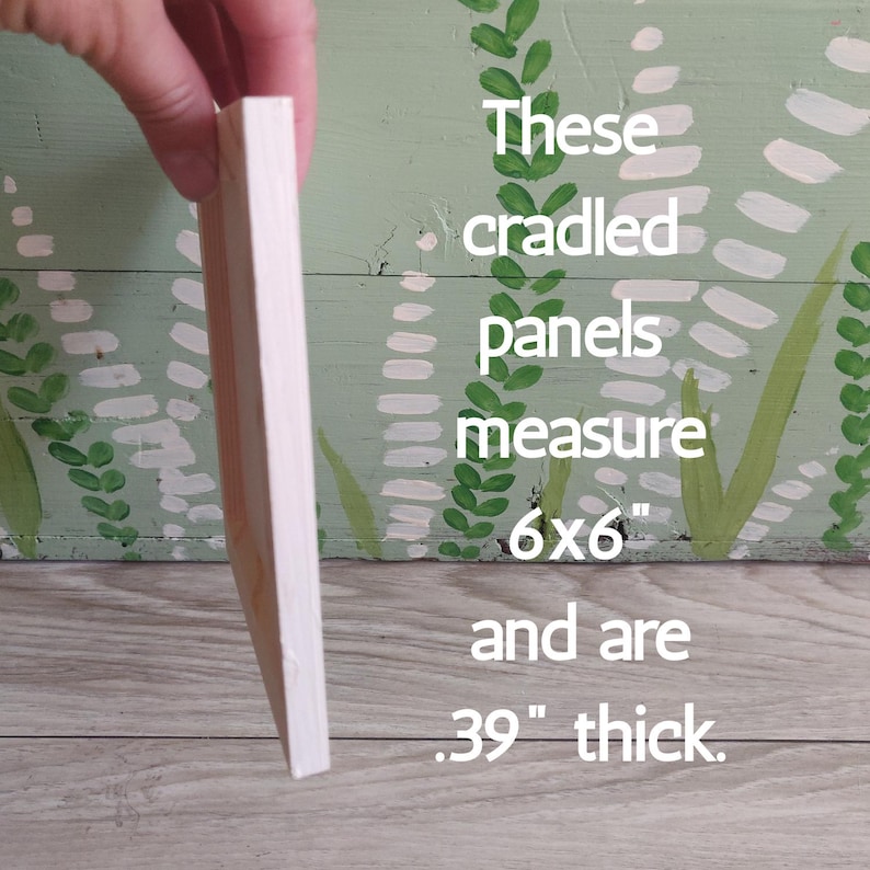 May include: A cradled panel, held by a hand, with a white painted edge. The panel measures 6x6 inches and is .39 inches thick. Text on the background reads "These cradled panels measure 6x6" and are .39" thick."