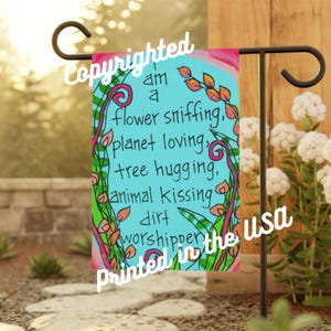 May include: A colorful garden flag with a blue background and green, orange, and pink floral designs. The text on the flag reads "I am a flower sniffing, planet loving, tree hugging, animal kissing dirt worshipper printed in the USA".