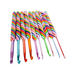 May include: A set of ten crochet hooks arranged in a row, each featuring a handle with a vibrant, multi-colored diagonal striped pattern. The metal hooks vary in size and color, including purple, blue, orange, pink, green, and red metallic finishes.