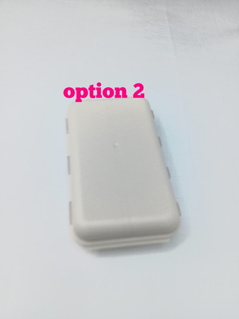 May include: A rectangular, light gray plastic storage case with rounded corners and a smooth surface. The text "option 2" is printed in pink above the case. The container features a hinged design with visible side latches for secure closure.