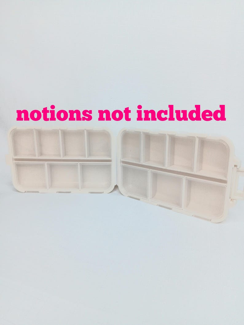 May include: Two open, off-white plastic storage containers with multiple rectangular compartments. The text "notions not included" is printed in bright pink letters above the containers. Each container features a hinged design with dividers.