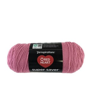 May include: A skein of dusty rose pink yarn with a black paper label featuring the Yarnspirations logo, a red heart icon, and the text Red Heart Super Saver. The label includes Oeko-Tex certification, care instructions, and weight information.