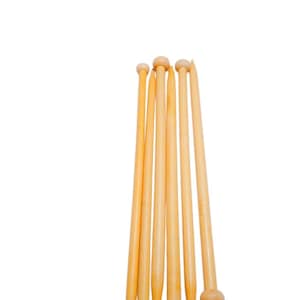 May include: A set of six light-colored wooden knitting needles arranged vertically. Each needle features a smooth, cylindrical shaft that tapers to a point at one end and terminates in a rounded knob at the other end, showing natural wood grain.