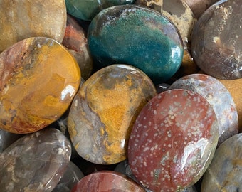 Puede incluir: Una colección de piedras pulidas y lisas en varios colores, incluyendo rojo, verde, marrón, amarillo y gris. Las piedras tienen una forma natural y orgánica y un acabado brillante. Las piedras varían en tamaño y forma, creando un surtido visualmente atractivo.