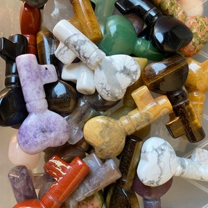 May include: A collection of gemstone key pendants in various colors and patterns. The pendants feature heart-shaped key heads and are made from materials like marble, tiger's eye, and jasper. The keys are of varying sizes.