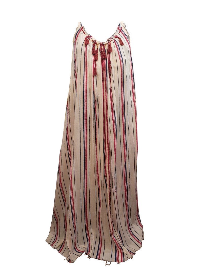 Puede incluir: Vestido largo y fluido con rayas verticales crema, azul marino y rojo. Cuenta con tirantes finos y un escote fruncido con borlas decorativas. La tela es ligera, ideal para climas c&aacute;lidos.