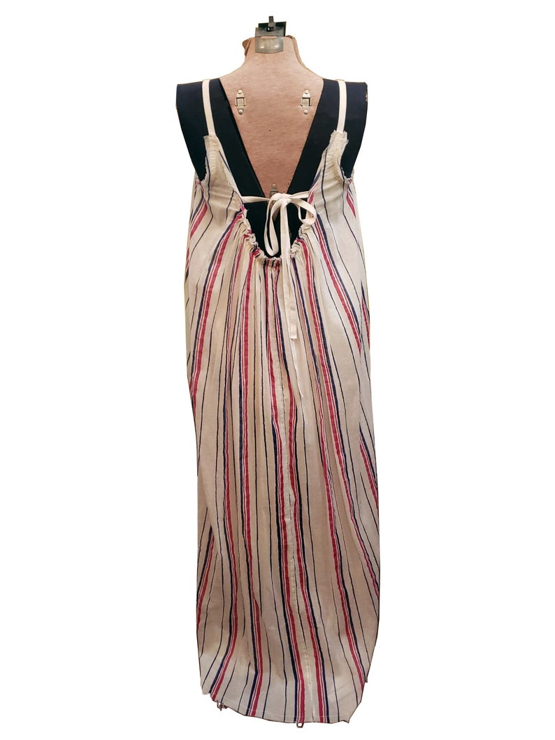 Puede incluir: Vestido largo sin mangas con espalda baja y rayas verticales rojas y azul marino sobre fondo crema. El vestido tiene un cierre de lazo en la espalda y se exhibe en un maniqu&iacute;.