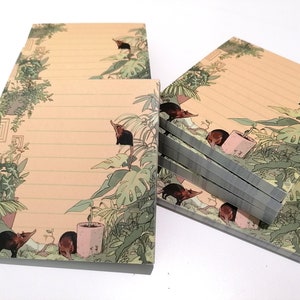 Può includere: Diverse pile di blocchi per appunti con un'illustrazione stravagante. Il design presenta uno sfondo beige chiaro con fogliame verde e piccoli animali. I blocchi per appunti hanno linee orizzontali per la scrittura.