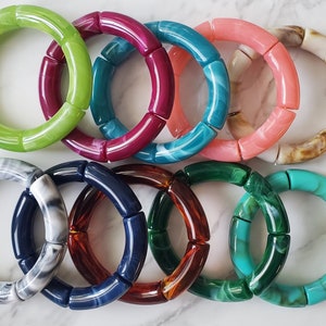 May include: Ten colorful bracelets made of round, chunky, marbled plastic. The bracelets are in various colors, including green, teal, pink, brown, white, red, blue, and turquoise.