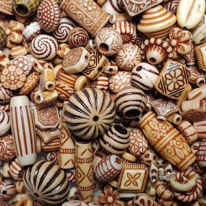 Peut inclure: Un assortiment de perles en bois avec différents motifs et designs. Les perles sont dans des tons de brun et crème, certaines présentant des détails complexes. Les perles sont parfaites pour la création de bijoux ou d'autres objets décoratifs.