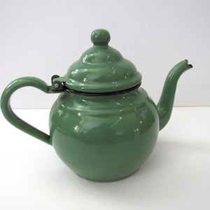 May include: A green enamel teapot with a lid and a spout. The teapot has a rounded body and a handle.