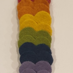 May include: A stack of felt hearts in rainbow colors, starting with red and ending with purple.