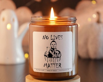 Può includere: Una candela di vetro marrone con un'etichetta bianca che recita "No Lives Matter". L'etichetta presenta un'illustrazione in bianco e nero di un uomo con un coltello. La candela è accesa e la fiamma è visibile.