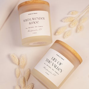 K&ouml;nnte beinhalten: Zwei gefrostete Glaskerzenbeh&auml;lter mit Holzdeckeln. Die Beh&auml;lter sind mit einem hellgelben Kerzenwachs gef&uuml;llt. Die Etiketten auf den Beh&auml;ltern lauten "Wild Lavender & Sage" und "Lily of the Valley". Beide Kerzen sind reine nat&uuml;rliche Sojawachskerzen und werden in Texas handgegossen. Jede Kerze wiegt 8 Unzen.