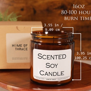 May include: A brown glass jar candle with a white label that reads "SCENTED SOY CANDLE". The candle is 3.95 inches (100.25 cm) tall and 3.55 inches (9.09 cm) wide. The candle has a burn time of 80-100 hours and is 16oz.