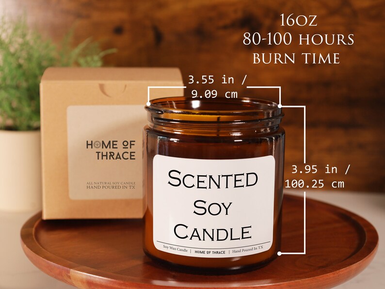 May include: A brown glass jar candle with a white label that reads "SCENTED SOY CANDLE". The candle is 3.95 inches (100.25 cm) tall and 3.55 inches (9.09 cm) wide. The candle has a burn time of 80-100 hours and is 16oz.